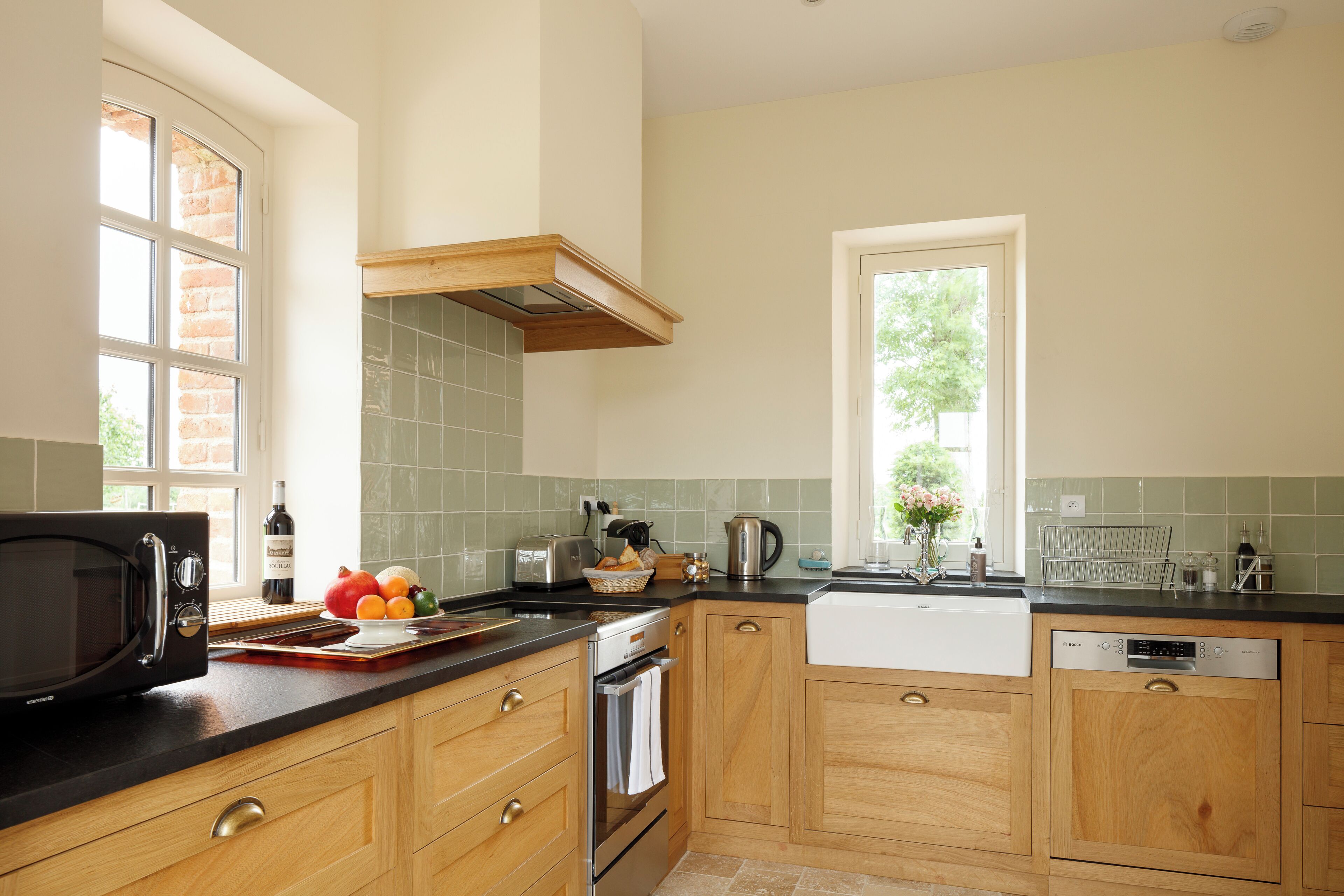 A kitchen with wooden cabinets, a black microwave, a toaster, and a sink.