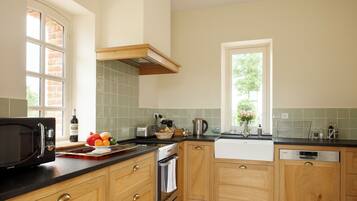 A kitchen with wooden cabinets, a black microwave, a toaster, and a sink.