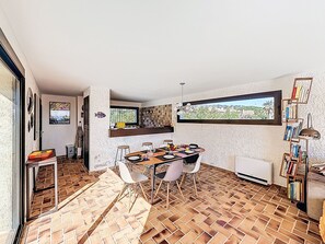 A dining area with a brick floor, a table set for four, and a bookshelf with books.