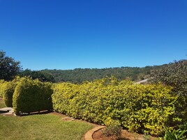 Un jardín ajardinado con setos bien cuidados y una vista despejada de un paisaje montañoso al fondo.