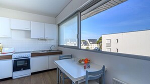 Ett modernt kök med vita skåp, en spis och ett fönster med utsikt över ett bostadsområde.