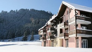 Un edifici d'àmbit elevat amb balcons, amb una muntanya nevada al fons.