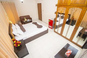 A hotel room with a large bed, a small desk, a chair, a wardrobe, and a mirror. - Hotel Suite Palace (Dhaka)