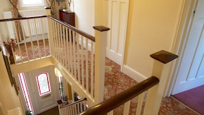 A multi-level interior with a staircase, a chandelier, and a door with a nameplate. - Moonraker House (Stratford-upon-Avon)