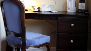 A hotel room with a wooden desk, a chair, a lamp, a coffee maker, and a dresser. - Moonraker House (Stratford-upon-Avon)
