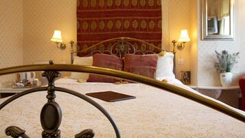 A bed with a patterned bedspread, two bedside lamps, a headboard, and a mirror on the wall.