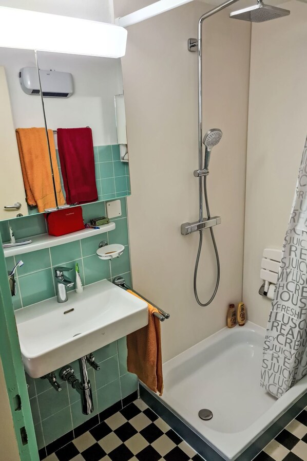 A bathroom with a shower, sink, and mirror.