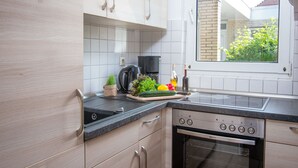 Eine moderne Küche mit hellen Holzschränken, einer schwarzen Arbeitsplatte, einem eingebauten Backofen und einem Fenster mit Blick auf Grünflächen.
