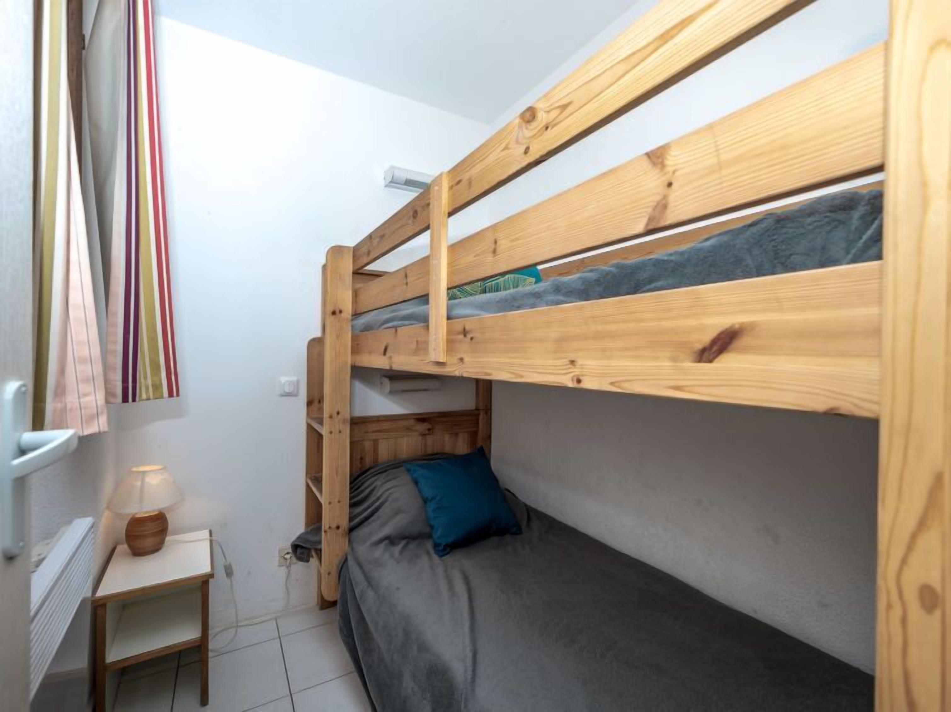 A bunk bed room with a small wooden table and a lamp.