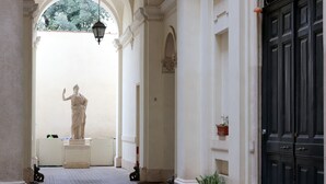 A corridor with a statue, columns, and a black door. - Trevi suites B&B (Rome)