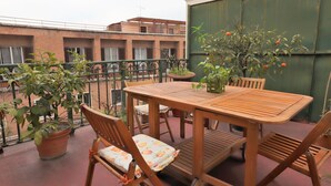 A wooden table and chairs on a balcony with potted plants and a view of buildings. - Trevi suites B&B (Rome)