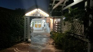 A hotel entrance at night with a 24-hour service sign, a reception area, and a paved pathway leading to the entrance. - Motel 24h (Lusciano)