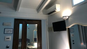 A bathroom with a mirror, a sink, a toilet, and a shower. There is a ceiling fan, a light fixture, and a wall-mounted TV. - Motel 24h (Lusciano)