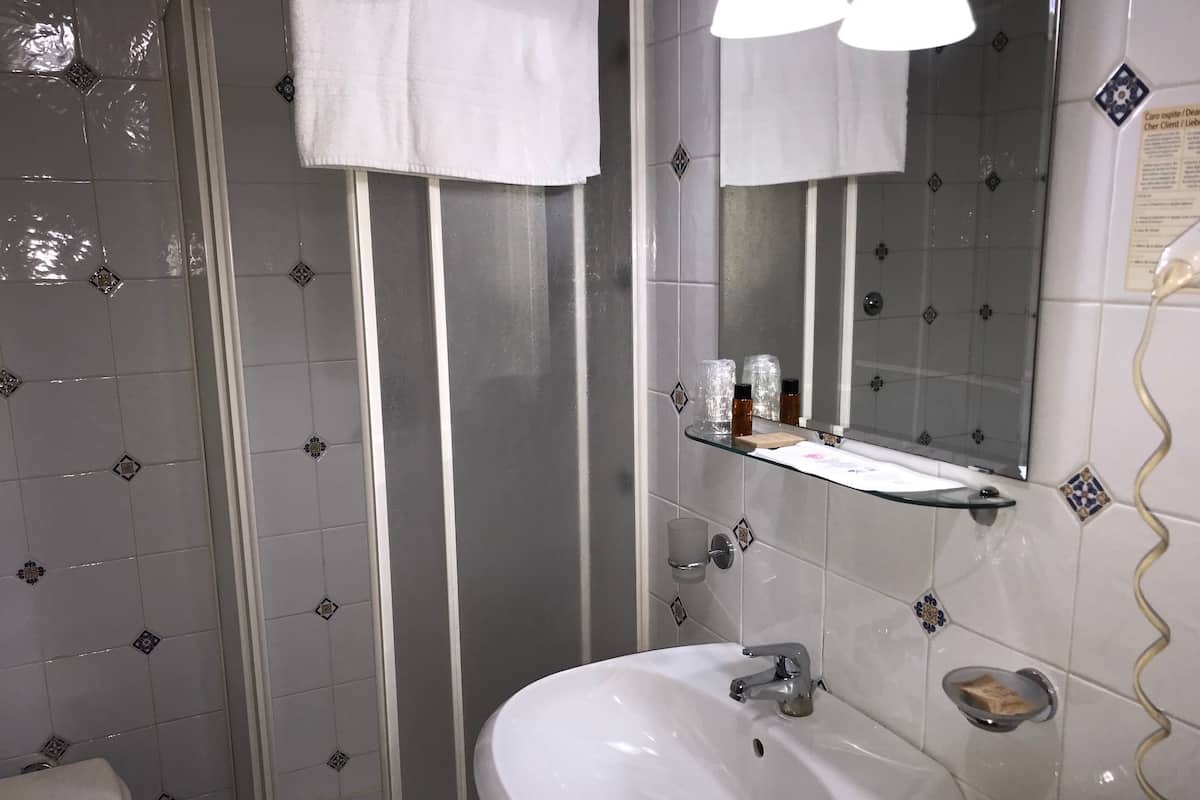 Une salle de bain comprenant des toilettes, un lavabo, un miroir et un espace douche.