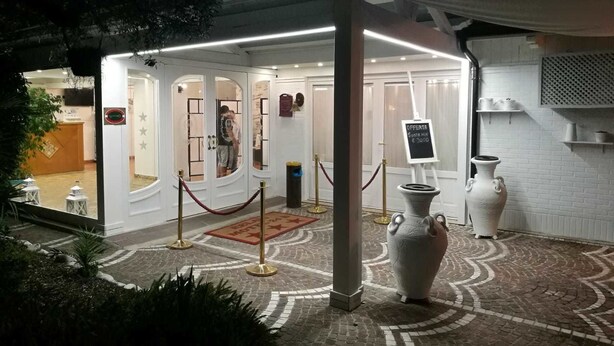 A hotel entrance with a glass door, a red carpet, and a sign indicating a sale. - Motel 24h (Lusciano)