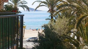Un balcon donnant sur une plage bordée de palmiers, avec une vue dégagée sur la mer.