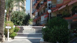 Une entrée fermée par un portail donnant accès à un immeuble résidentiel, avec une enseigne indiquant « TURIA ».