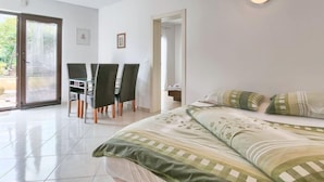 A bedroom with a bed, a desk with chairs, and a door leading to an outdoor area. - Villa Alpa by Interhome (Umag)