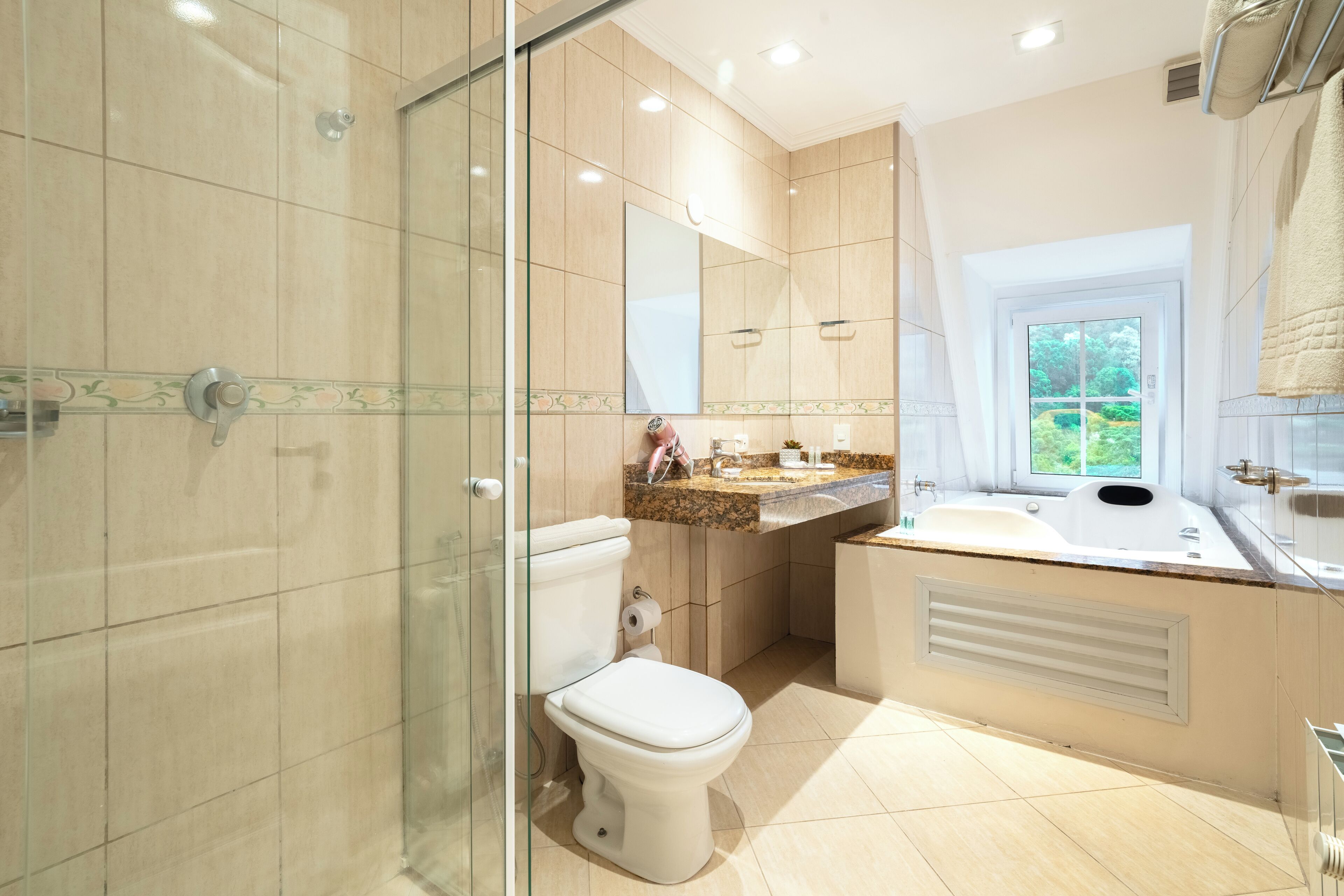 A modern bathroom with a glass shower enclosure, a toilet, a sink with a vanity, and a large mirror.