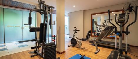 A gym with various exercise equipment, including a treadmill, elliptical, and weight machines.