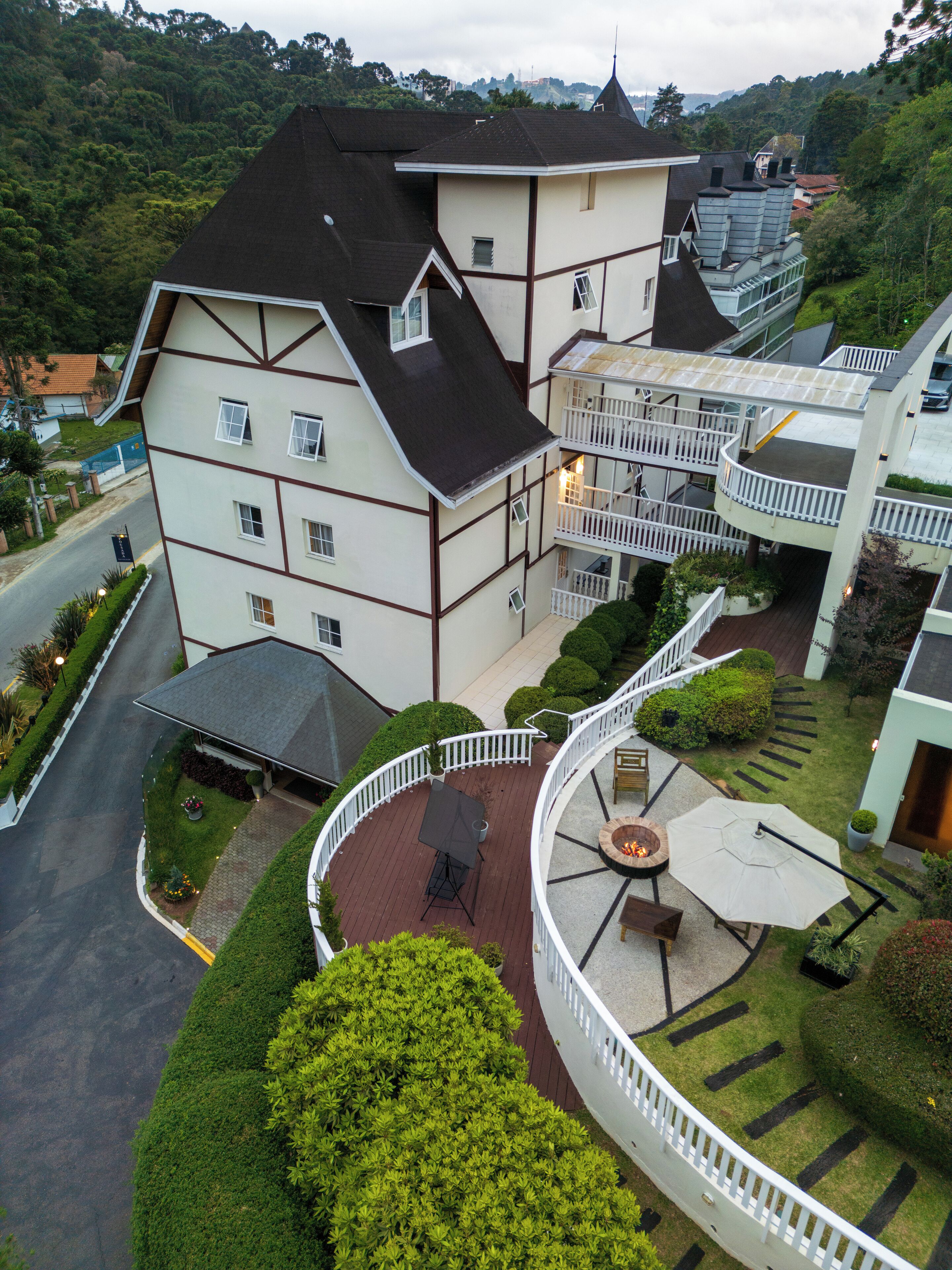Um edifício de vários andares com uma varanda curva, uma lareira e um jardim bem cuidado.