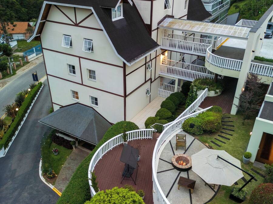 A multi-story building with a curved balcony, a fire pit, and a well-maintained garden.