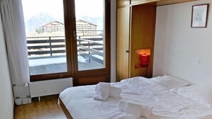 A hotel room with a bed, a window with a view of mountains, and a red wall-mounted light. - Christiania I I4 by Interhome (Nendaz)