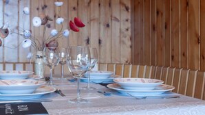 A dining table set with plates, bowls, and wine glasses, with a menu and a vase of flowers. - Christiania I I4 by Interhome (Nendaz)