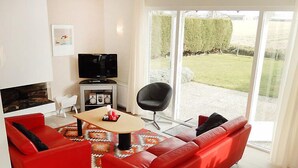 A modern living room with a red sofa, a black chair, and a television. - Stern Comfort by Interhome (Noordwijk)