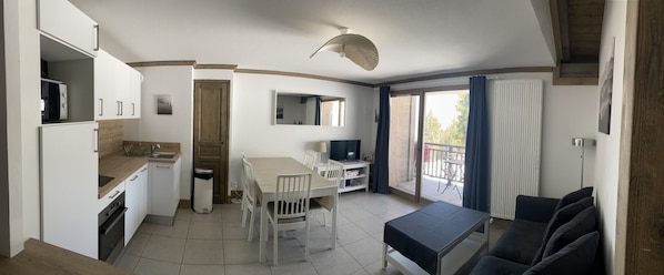 Un espacio habitable compacto con kitchenette, comedor y balcón.