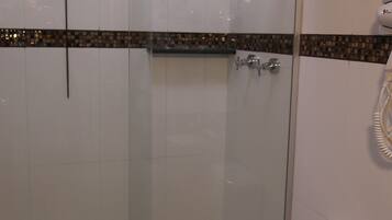 Uma casa de banho moderna com cabine de duche em vidro, sanita branca e lavatório preto.