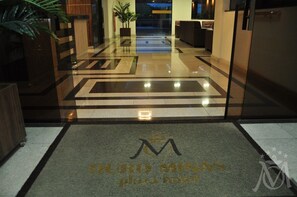 A hotel entrance with a polished floor, a reception desk, and a plant. - Ouro Minas Plaza Hotel (Aparecida)
