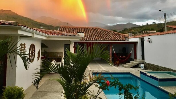 A house with a tiled roof, a swimming pool, and a hammock.