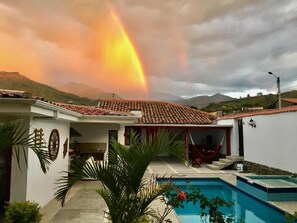 A house with a tiled roof, a swimming pool, and a hammock. - Hostel las Palmas (Vilcabamba)