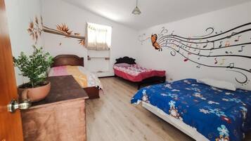 A bedroom with two beds, a wooden cabinet, a potted plant, and wall art.