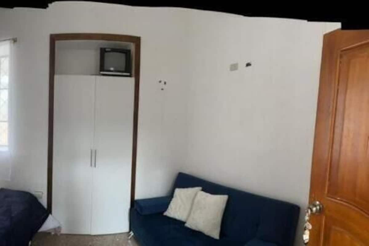 A bedroom with two beds, a wardrobe, a small table, and a window.