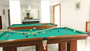 A pool table with balls and cues, a mirror on the wall, and a door leading to another room. - Estrelas Da Serra (Gramado)
