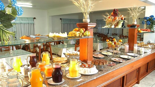 A buffet with various food items and beverages, including fruits, pastries, and juices. - Estrelas Da Serra (Gramado)