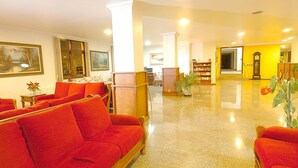A hotel lobby with red sofas, a wooden reception desk, and a large clock on the wall. - Estrelas Da Serra (Gramado)