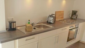 A modern kitchen with a stainless steel sink, a toaster, a coffee maker, and a built-in oven.