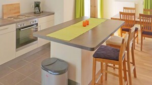 A compact kitchen with a central island, a coffee maker, and a trash bin.