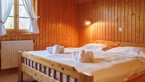 A wooden room with a bed, a window with curtains, and a radiator. - Notre Rêve by Interhome (Zinal)