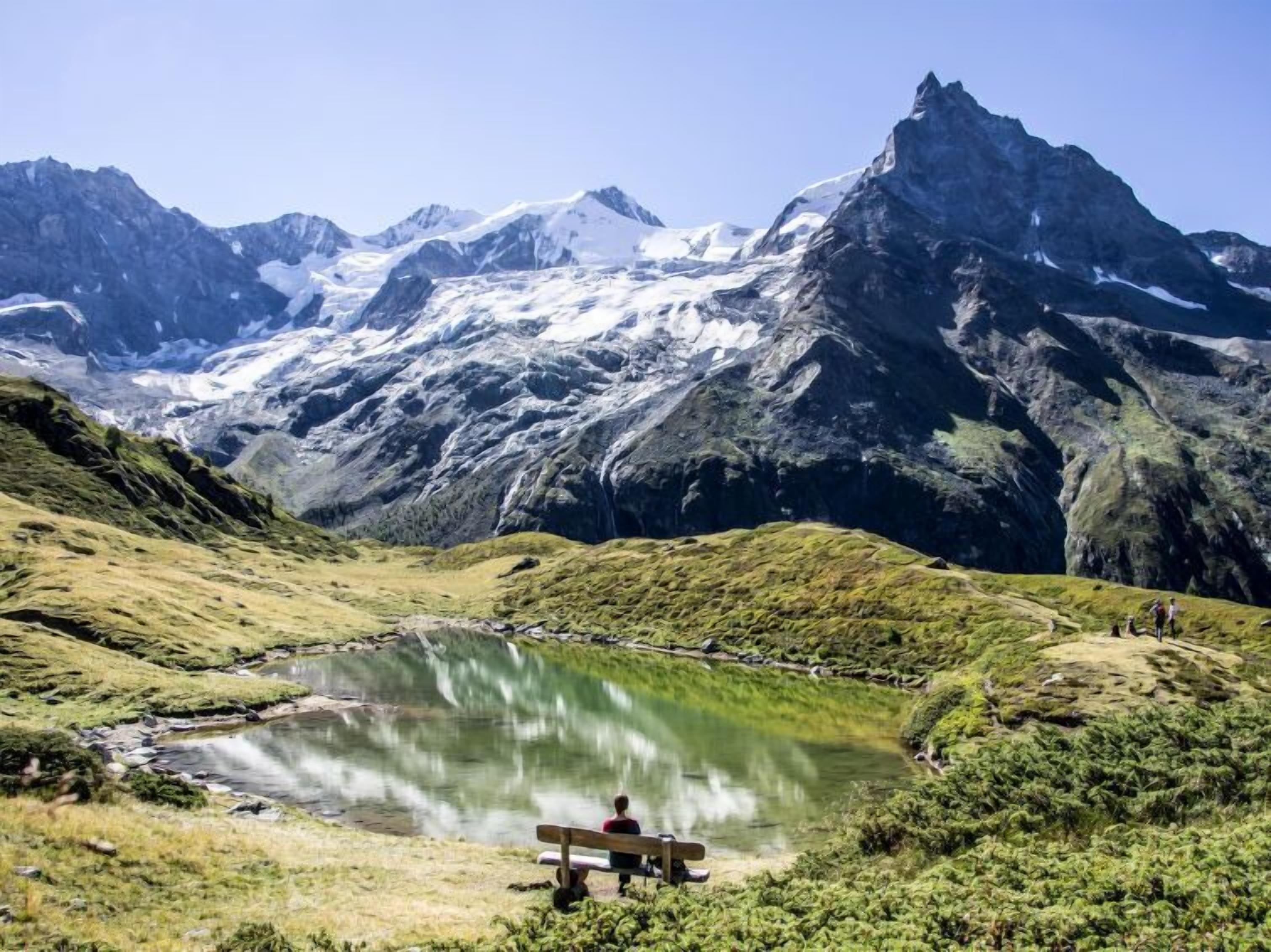 A mountain landscape with a lake and a bench.