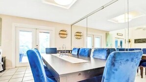 A conference room with a long table and blue chairs, large windows, and a glass partition. - Spacious, Relaxing, Family-Friendly Townhouse Retreat Steps from Pool & Beach (Destin)
