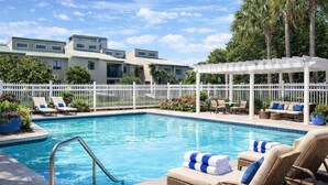 A swimming pool with lounge chairs and a pergola, surrounded by a white fence and palm trees. - Spacious, Relaxing, Family-Friendly Townhouse Retreat Steps from Pool & Beach (Destin)