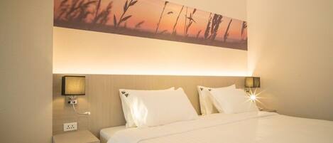 Habitación de hotel con una cama grande, dos lámparas de noche, una mesita de noche y un cuadro colgado en la pared.