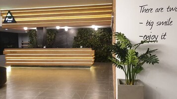 A reception area with a wooden reception desk, a sign above it, and a wall with a motivational quote.