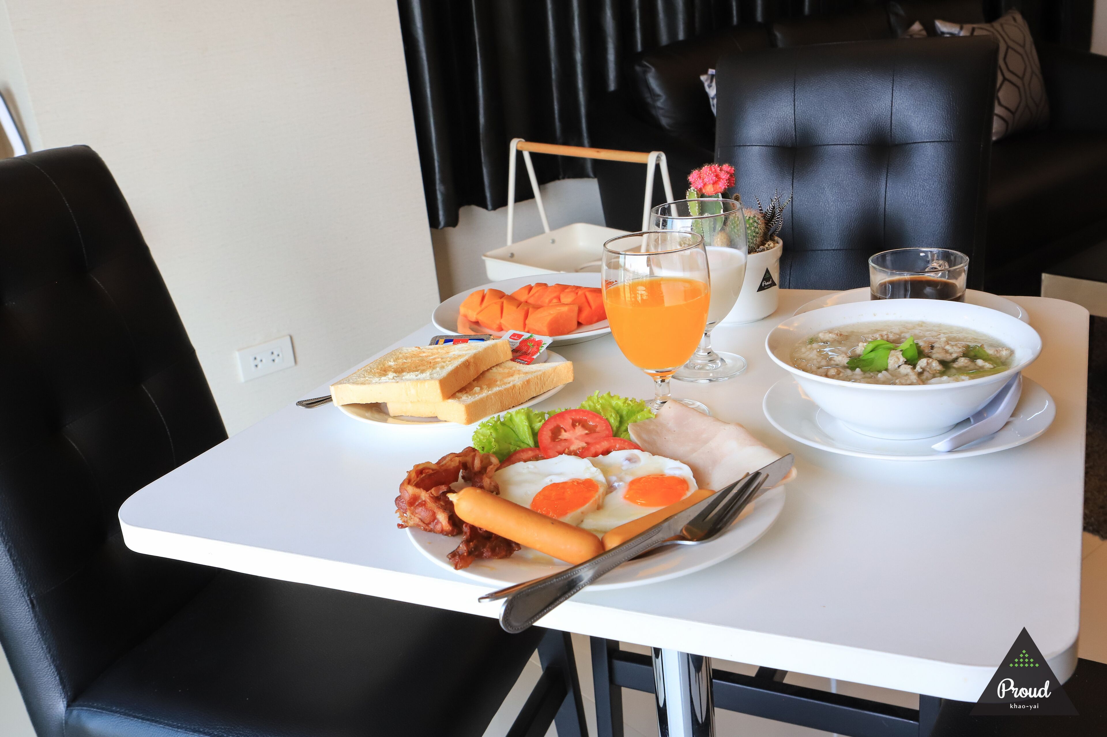 A breakfast table with toast, eggs, bacon, and a bowl of soup.