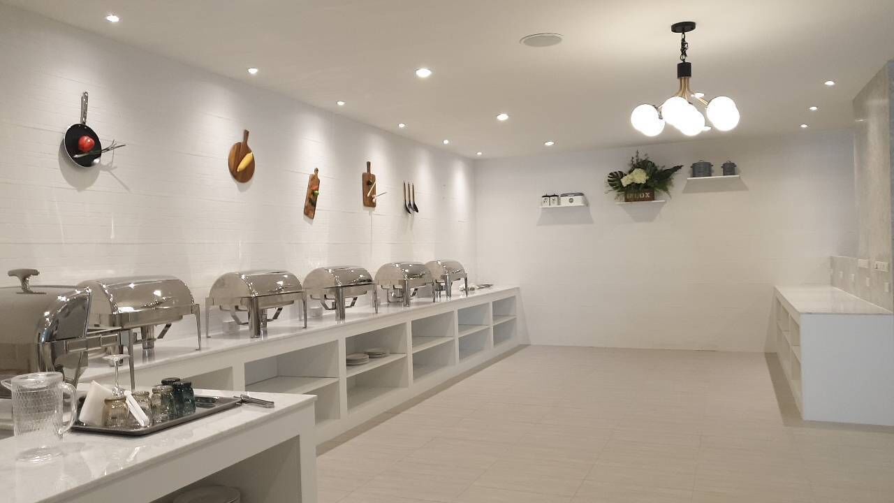 Une pièce moderne et bien éclairée, dotée d’un long comptoir, de plusieurs chaises, ainsi que d’une variété d’ustensiles et d’appareils de cuisine.