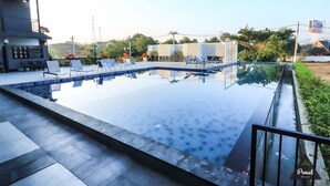 A swimming pool with lounge chairs and a black railing. - Proud Khaoyai (Pak Chong)